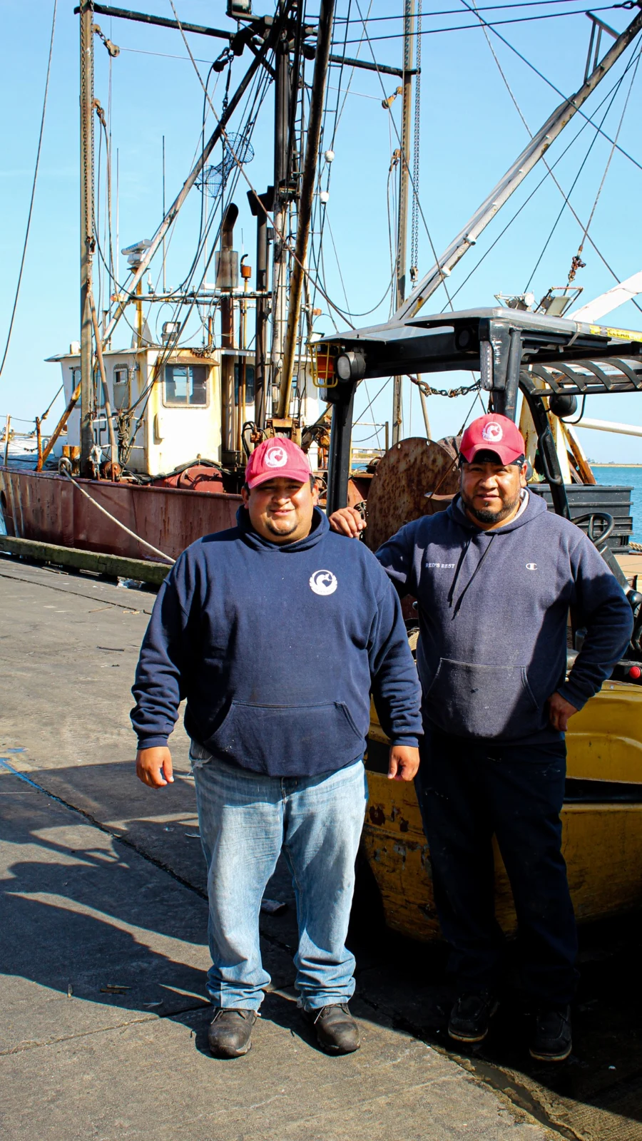 Red’s Best team members on the working waterfront beside a fishing boat and forklift